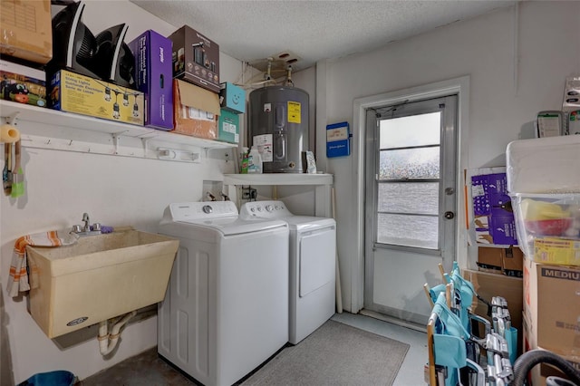 washroom featuring electric water heater, washer and clothes dryer, a textured ceiling, and sink