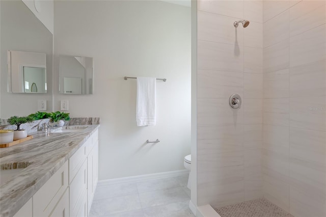 bathroom with tiled shower, tile patterned flooring, vanity, and toilet