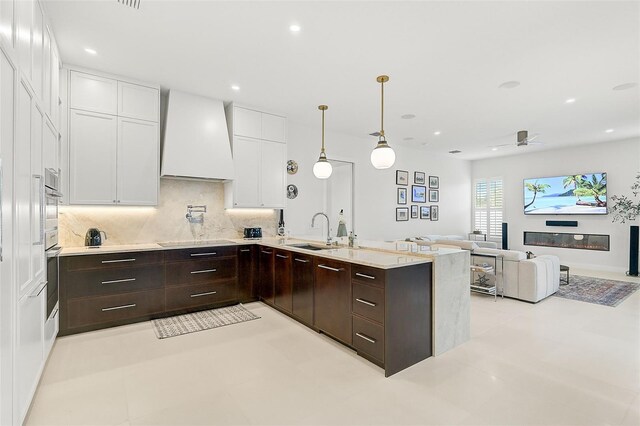 2112 Calusa Lakes Blvd, Nokomis, FL 34275 - kitchen featuring premium range hood, white cabinets, tasteful backsplash, dark brown cabinets, and a peninsula