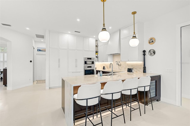 2112 Calusa Lakes Blvd, Nokomis, FL 34275 - kitchen featuring custom range hood, double oven, a peninsula, tasteful backsplash, and a breakfast bar area