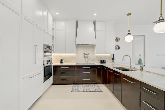 kitchen featuring custom exhaust hood, sink, decorative backsplash, decorative light fixtures, and white cabinetry