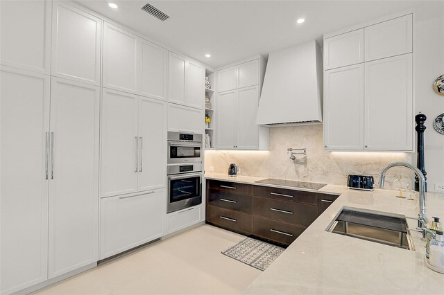 2112 Calusa Lakes Blvd, Nokomis, FL 34275 - kitchen with premium range hood, black electric cooktop, white cabinets, dark brown cabinetry, and recessed lighting