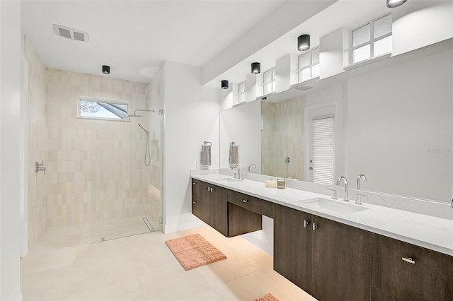 bathroom featuring tile patterned flooring, vanity, and tiled shower