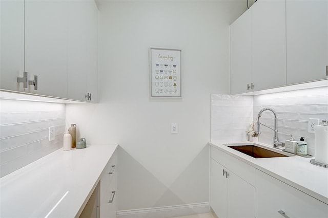 kitchen featuring tasteful backsplash, white cabinetry, and sink