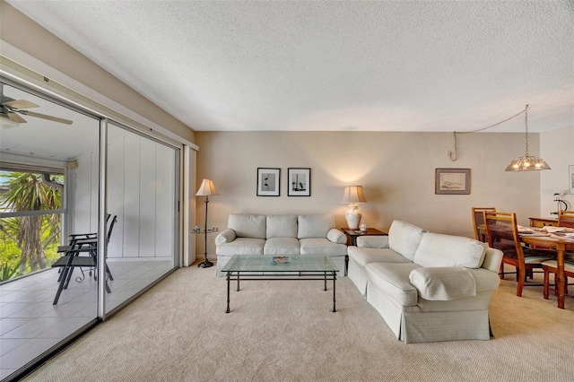 living room with ceiling fan, light colored carpet, and a textured ceiling