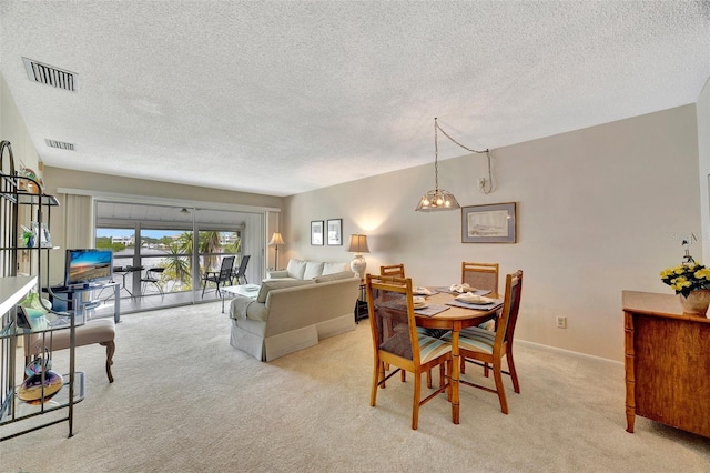 dining area featuring a chandelier, light colored carpet, and a textured ceiling