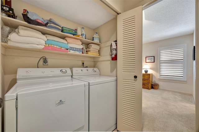 laundry room with separate washer and dryer, a textured ceiling, and light colored carpet