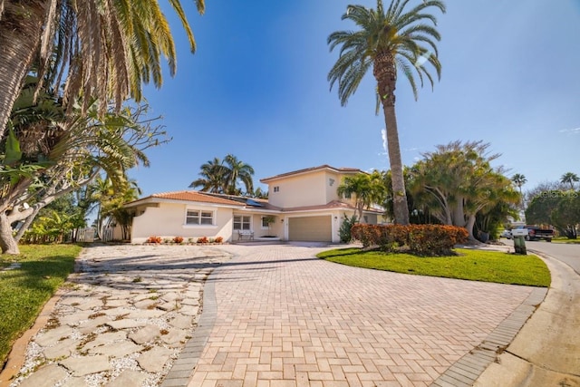 mediterranean / spanish home with a garage, a front yard, and solar panels