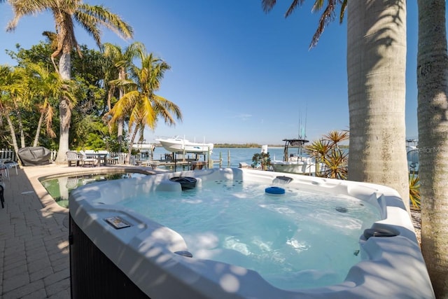 view of pool with a hot tub, a water view, and a dock