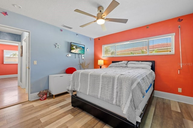 bedroom featuring a textured ceiling, light hardwood / wood-style flooring, and ceiling fan