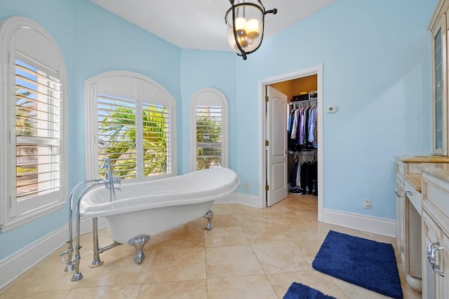 bathroom with tile patterned floors, a bathtub, vanity, and a notable chandelier