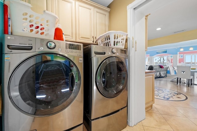 laundry room featuring washer and dryer, light tile patterned floors, and cabinets