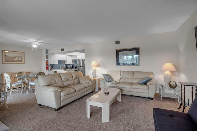 living room featuring carpet, ceiling fan, and sink