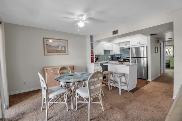 dining room featuring dark colored carpet, ceiling fan, and sink