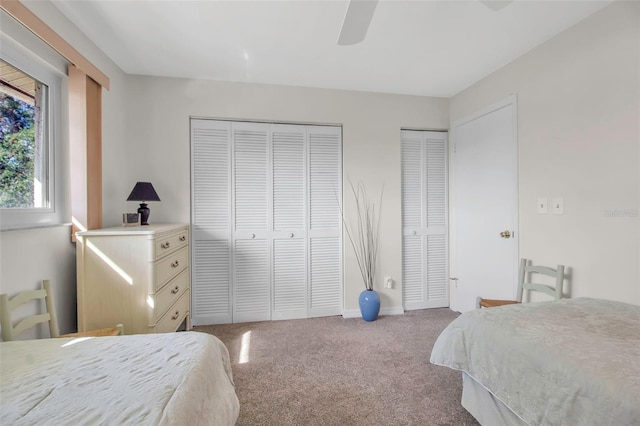 bedroom with carpet floors, ceiling fan, and multiple closets