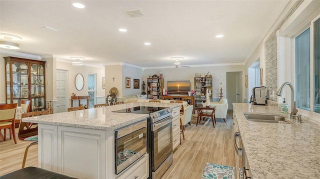 kitchen featuring a kitchen bar, ceiling fan, sink, electric stove, and white cabinetry