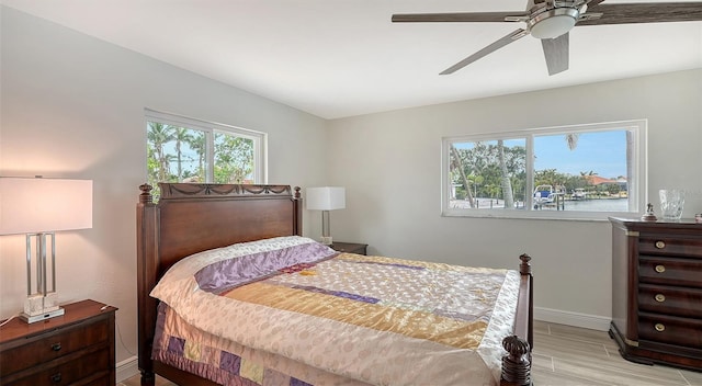 bedroom with a water view, light hardwood / wood-style flooring, and ceiling fan