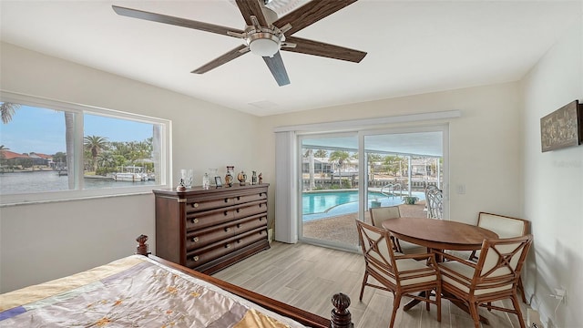 bedroom with ceiling fan, access to exterior, a water view, and light hardwood / wood-style flooring