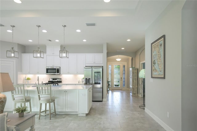 kitchen with hanging light fixtures, white cabinetry, a center island with sink, and stainless steel appliances