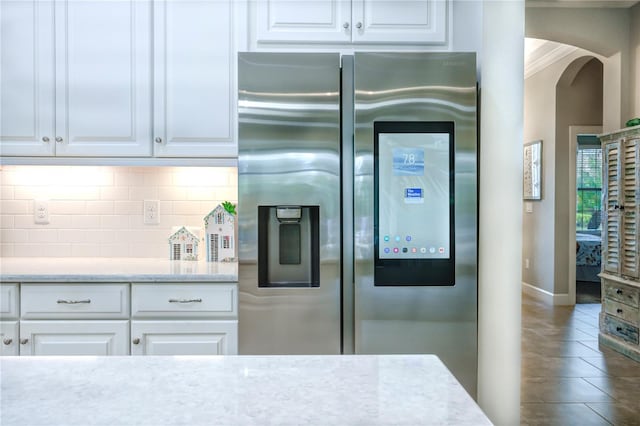 kitchen featuring white cabinets, stainless steel fridge with ice dispenser, ornamental molding, and tasteful backsplash