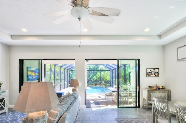 entryway featuring a tray ceiling, dark tile patterned flooring, and ceiling fan