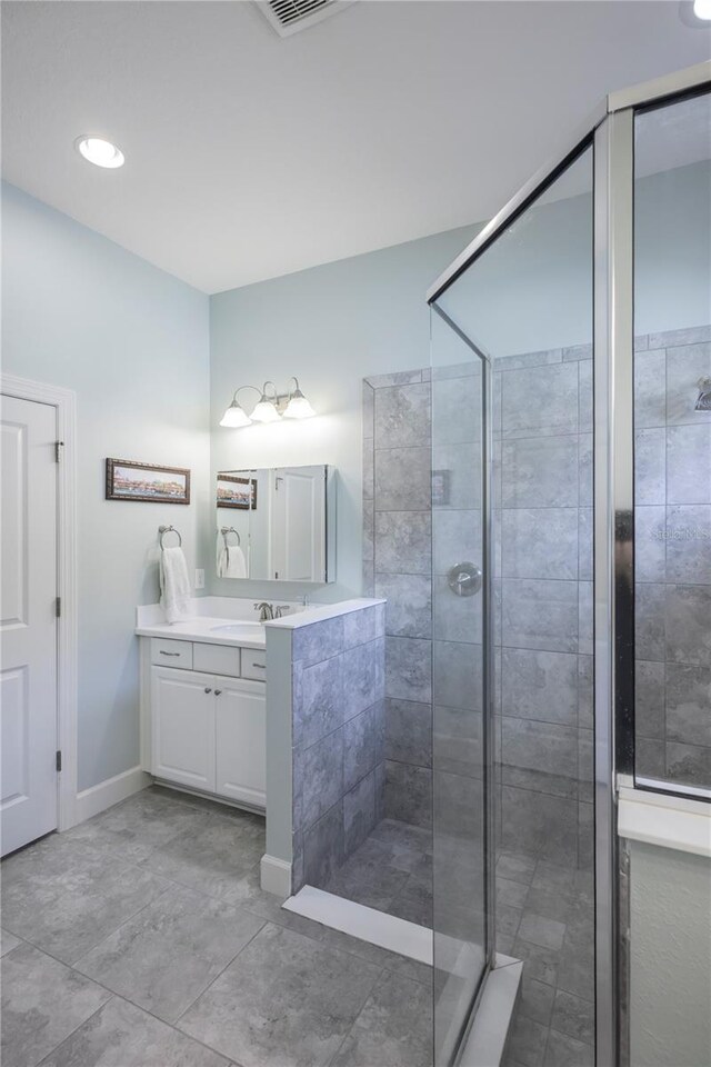 bathroom featuring tile patterned flooring, a tile shower, and vanity