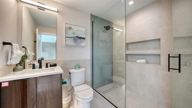 bathroom with walk in shower, vanity, toilet, and tile walls