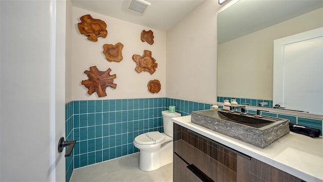 bathroom featuring tile patterned floors, vanity, toilet, and tile walls