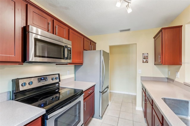 kitchen featuring a textured ceiling, light tile patterned floors, sink, and appliances with stainless steel finishes