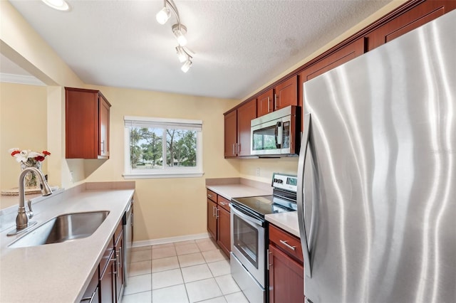 kitchen featuring sink, light tile patterned floors, a textured ceiling, and appliances with stainless steel finishes