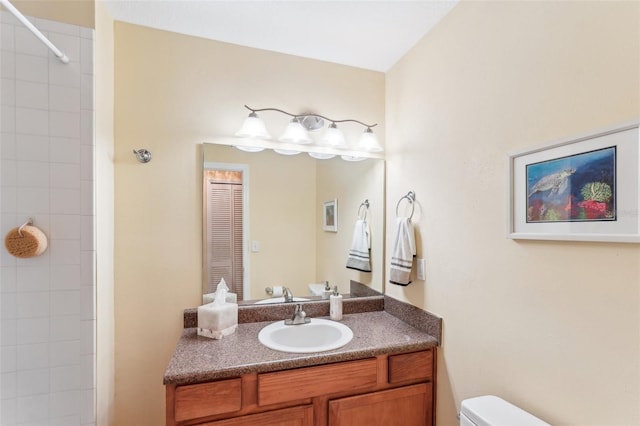 bathroom featuring a tile shower, vanity, and toilet