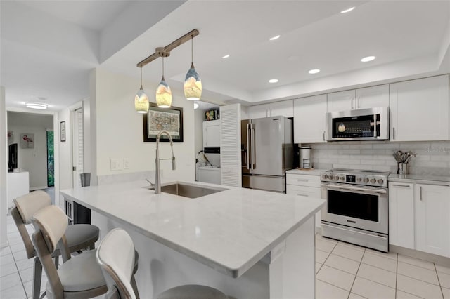 kitchen with sink, hanging light fixtures, stainless steel appliances, kitchen peninsula, and white cabinets