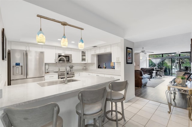 kitchen featuring ceiling fan, tasteful backsplash, decorative light fixtures, white cabinetry, and stainless steel appliances