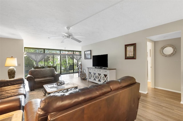 living room featuring floor to ceiling windows, a textured ceiling, light hardwood / wood-style floors, and ceiling fan