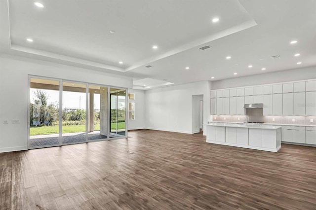 8007 Nevis Run, Bradenton, FL 34202 - unfurnished living room featuring a raised ceiling, baseboards, plenty of natural light, and recessed lighting