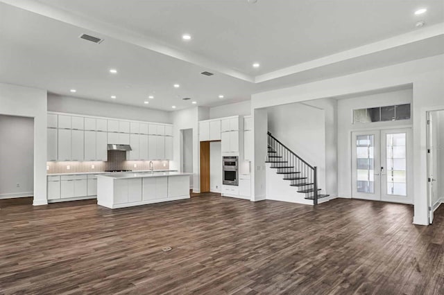 8007 Nevis Run, Bradenton, FL 34202 - kitchen with under cabinet range hood, dark wood-style flooring, french doors, tasteful backsplash, and recessed lighting