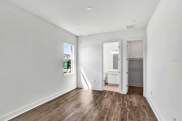 8007 Nevis Run, Bradenton, FL 34202 - unfurnished bedroom featuring wood finished floors, a spacious closet, baseboards, a closet, and ensuite bath