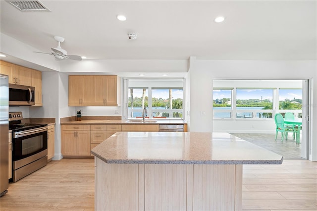 kitchen with light brown cabinetry, light stone counters, sink, and stainless steel appliances