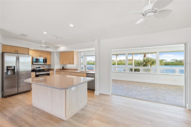 kitchen with sink, a kitchen island, stainless steel appliances, and light wood-type flooring