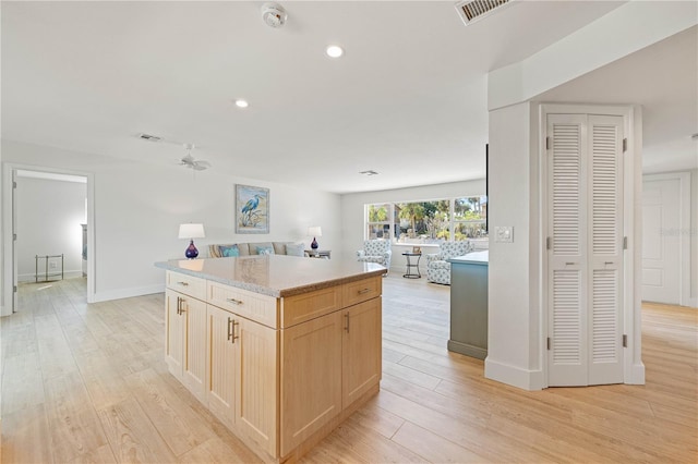 kitchen featuring ceiling fan, a center island, light wood-type flooring, and light brown cabinetry