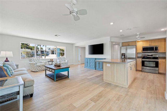 kitchen with ceiling fan, a kitchen island, appliances with stainless steel finishes, and light hardwood / wood-style flooring