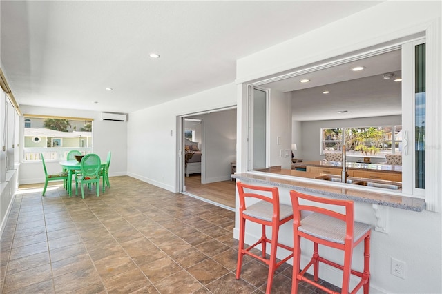 kitchen with a wall mounted air conditioner, a breakfast bar area, and sink