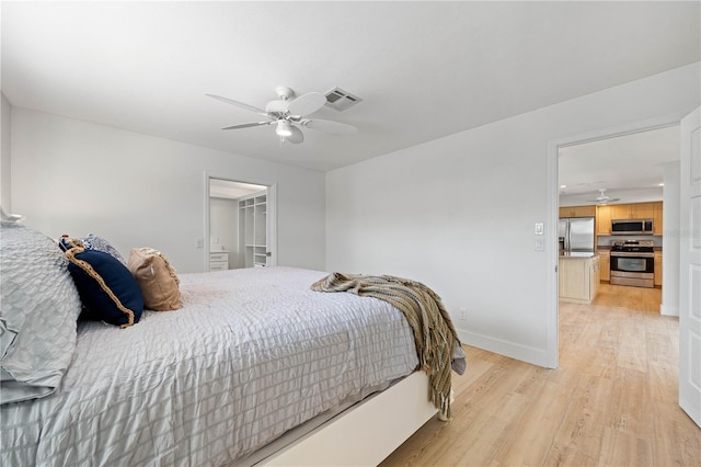 bedroom featuring a spacious closet, ceiling fan, stainless steel fridge, light hardwood / wood-style floors, and a closet