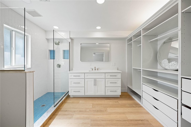 bathroom with hardwood / wood-style floors, vanity, and a tile shower