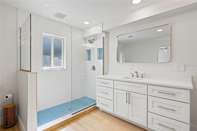 bathroom with hardwood / wood-style flooring, vanity, and a tile shower