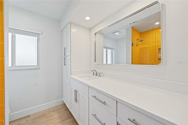 bathroom with hardwood / wood-style flooring, vanity, and a tile shower