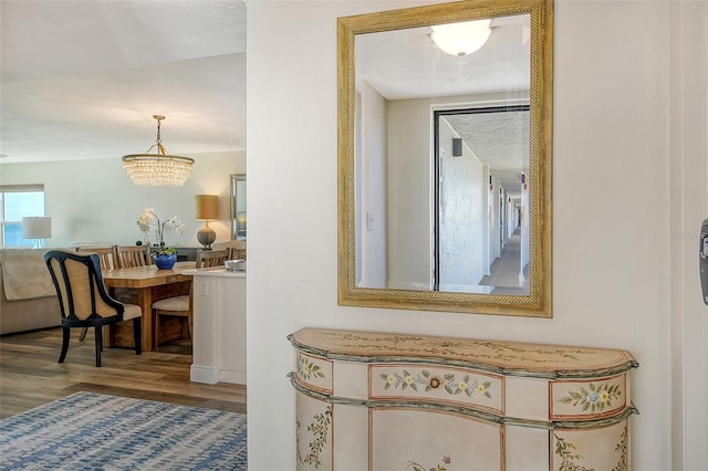 hallway with hardwood / wood-style flooring and a notable chandelier