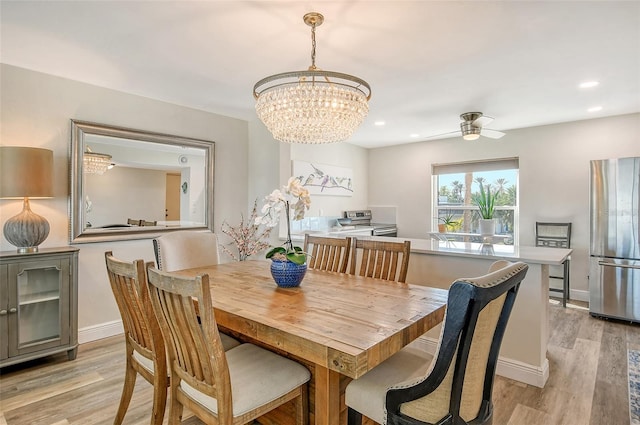 dining room featuring light hardwood / wood-style floors and ceiling fan with notable chandelier