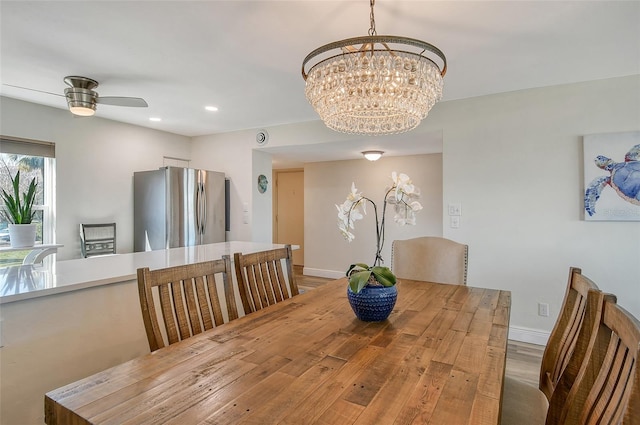 dining area with hardwood / wood-style floors and ceiling fan with notable chandelier