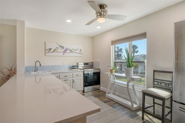 kitchen featuring electric stove, sink, ceiling fan, dark hardwood / wood-style flooring, and white cabinetry